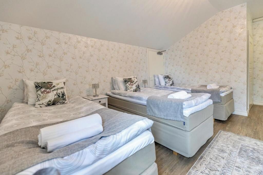 A bedroom with two beds, a nightstand, and a mirror.