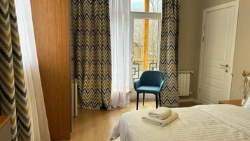 Een slaapkamer met een bed, een stoel, een kledingkast en een raam met gordijnen.