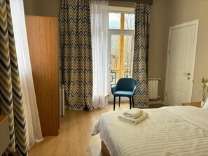 A bedroom with a bed, a chair, a wardrobe, and a window with curtains. - RestArt Boutique Hotel (Dilijan)