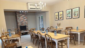 A dining area with multiple tables and chairs, a laptop on one table, and framed artwork on the wall. - RestArt Boutique Hotel (Dilijan)