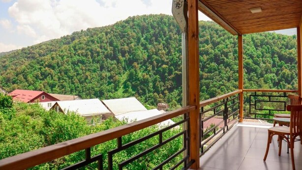 A wooden balcony with a view of a forested mountain. - RestArt Boutique Hotel (Dilijan)