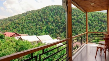 Un balcón de madera con vista a una montaña boscosa.