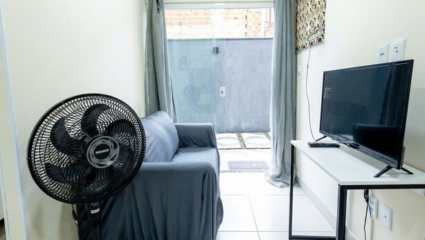 Een kamer met een bed, een bureau met een televisie en een ventilator.