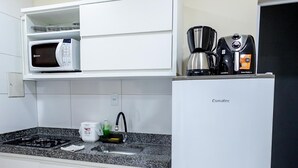 Een keuken met een magnetron, koffiezetapparaat en een koelkast.
