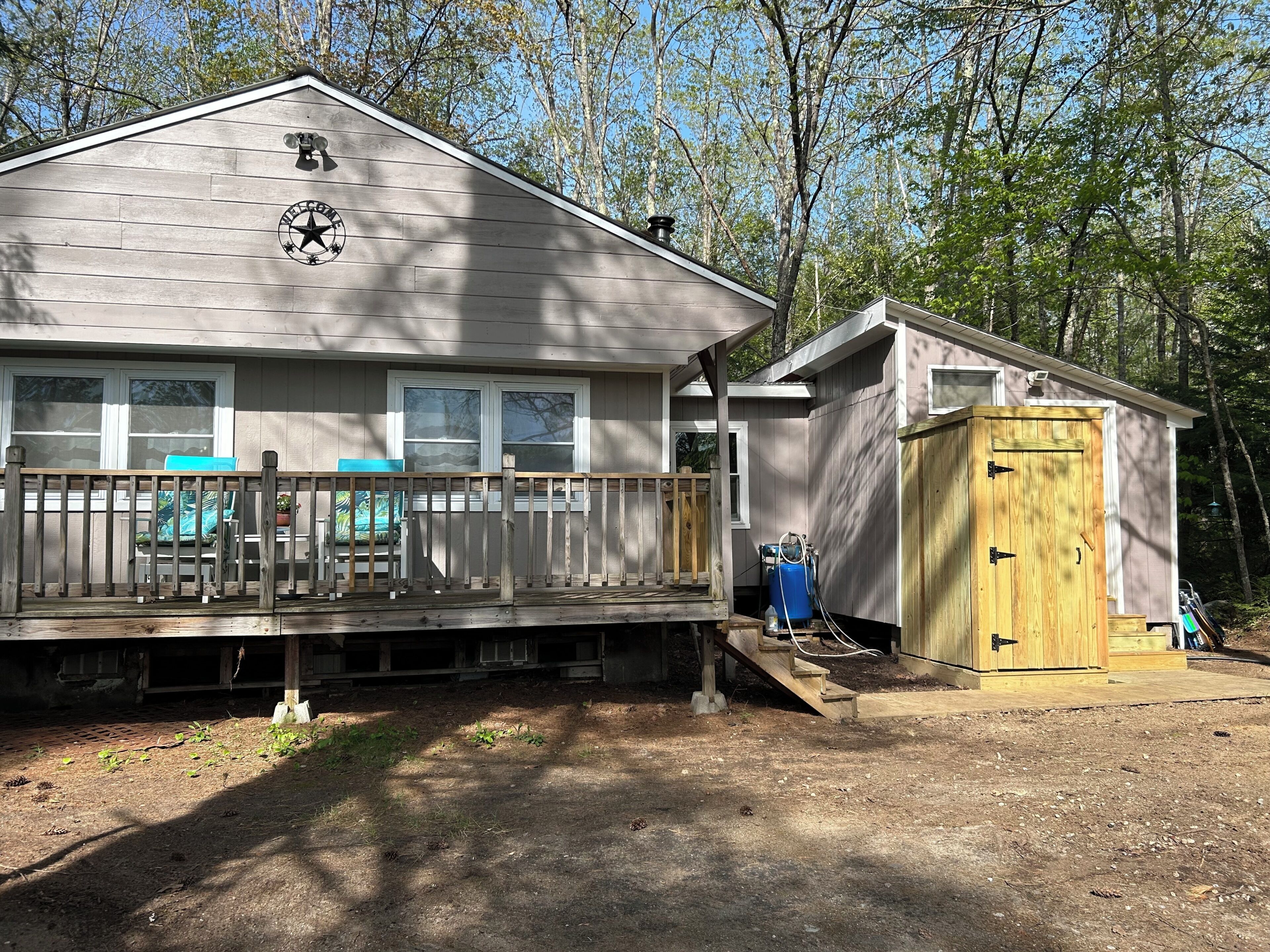 A cabin with a porch, a small shed, and a deck with outdoor seating.
