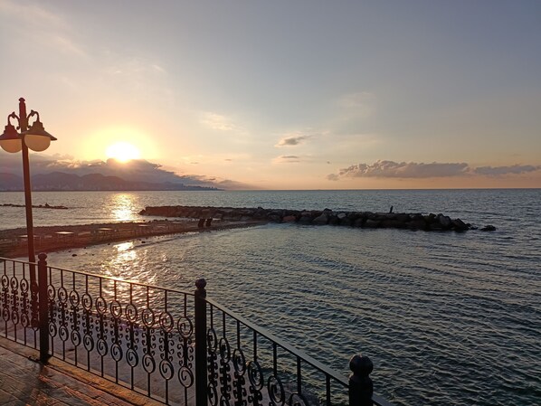 Une promenade en bord de mer, agrémentée d’une rambarde, d’un lampadaire et offrant une vue sur la mer.