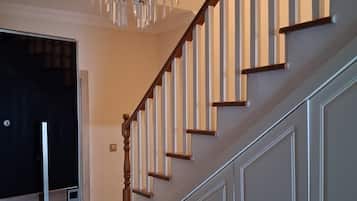 A staircase with wooden steps and a glass railing, leading to a landing with a door.