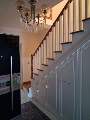 A staircase with wooden steps and a glass railing, leading to a landing with a door. - GREEN PEARL PANSİYON (Fatsa)
