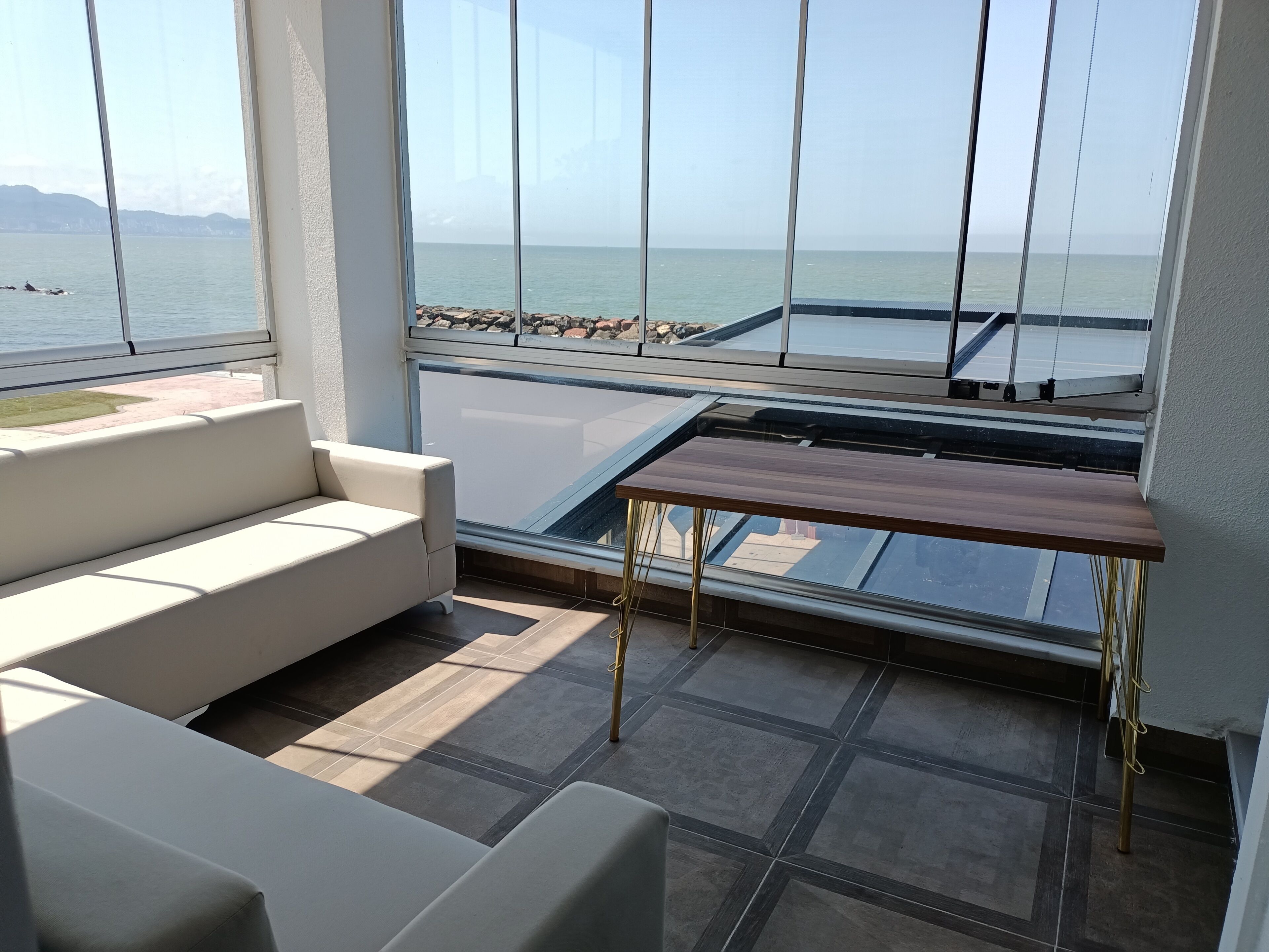 Ein Balkon mit einer Couch, einem Tisch und Meerblick.