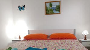 Un llit ben fet amb almoades taronges, un llençol floral i tovalloles enrotllades en verd i blau.