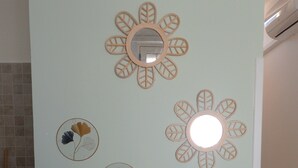 Una habitació amb una paret blau cel, un mirall amb marc circular i quatre ornaments murals circulars amb motius de fulles.