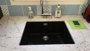 Un lavamanos con grifo, una botella de jabón de manos y una botella de lavavajillas.