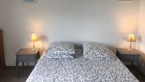 Un dormitorio con cama, dos mesitas de noche, dos lámparas y dos cuadros en la pared.