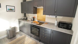 A modern kitchen with dark cabinets, a built-in oven, a microwave, and a toaster. - Corner House, close to Lincoln City Centre (Lincoln)