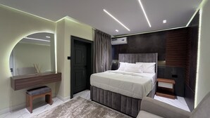 Un dormitorio moderno con cama, mesitas de noche, tocador y un espejo grande.