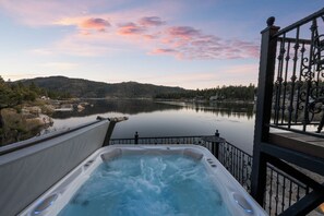 A hot tub with a view of a lake and mountains.