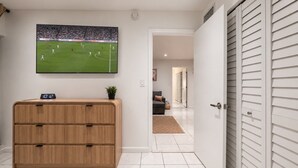 Een kamer met een televisie waarop een sportevenement wordt vertoond, een houten kast en een schuifdeur naar een andere kamer.
