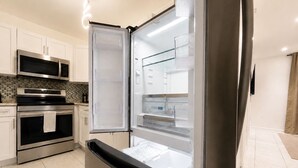Een moderne keuken met roestvrijstalen apparatuur, een inbouwoven en een koelkast met glazen deur.