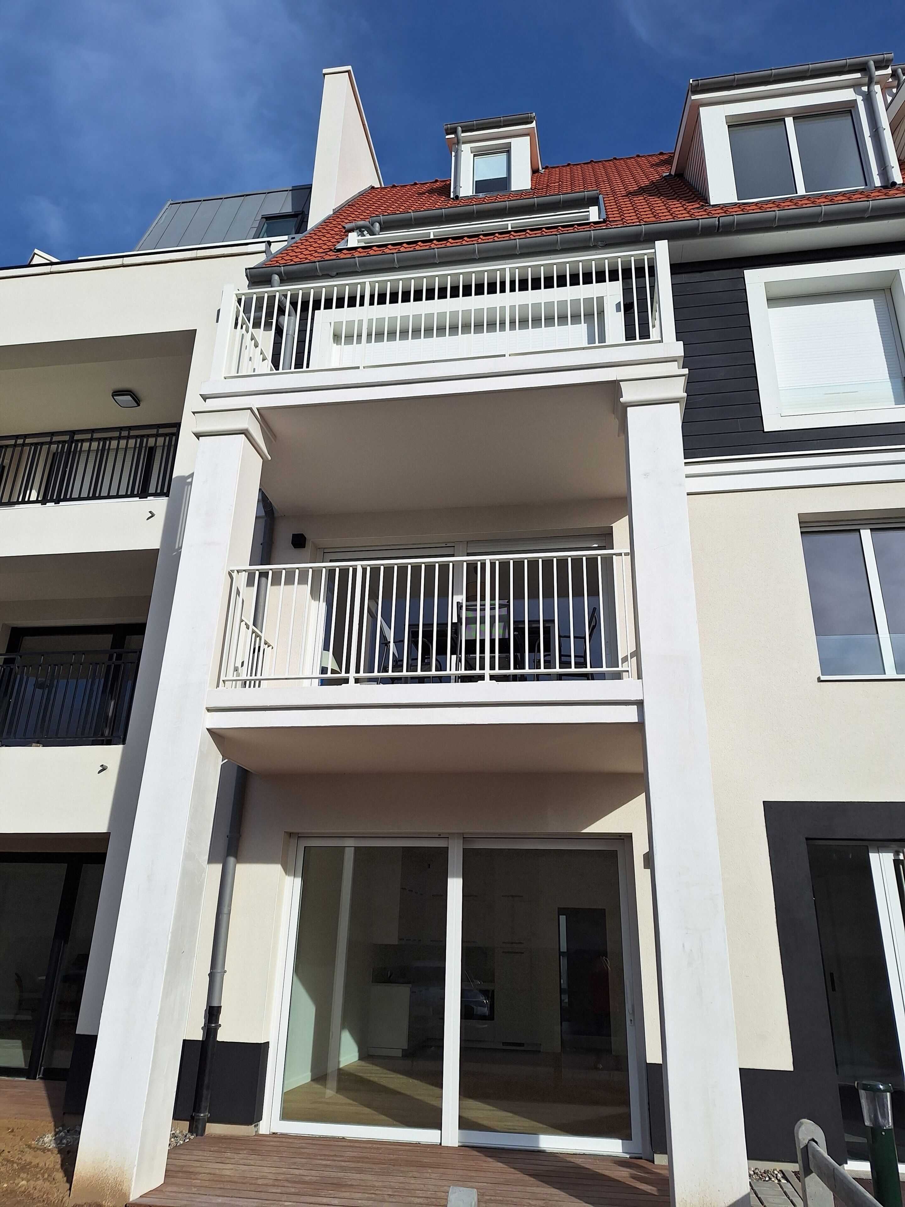 Un immeuble résidentiel à plusieurs étages, doté de balcons, de grandes fenêtres et d’un toit plat.