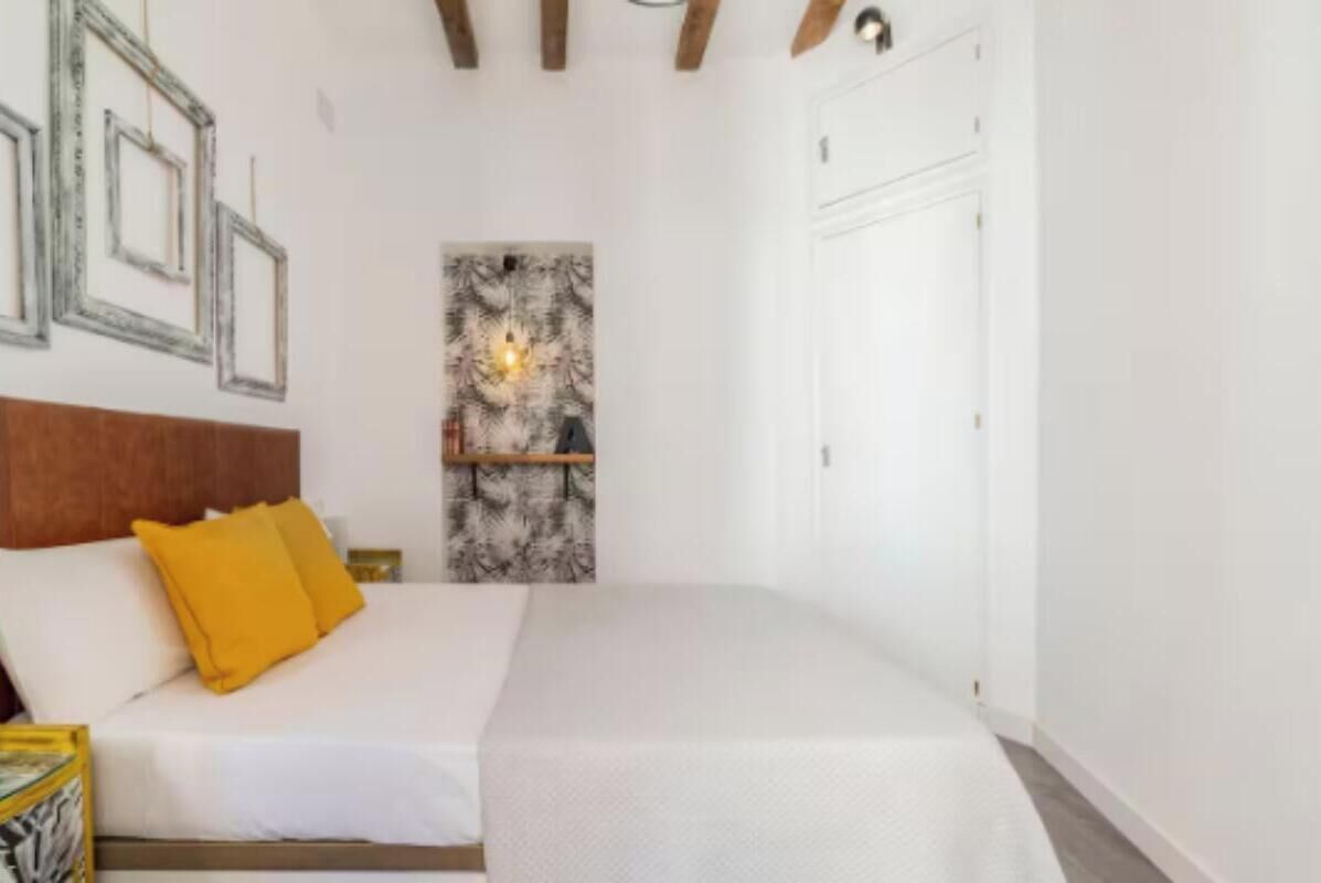 Ein Schlafzimmer mit einem Bett, einem Kopfteil, einem Wandbild und einer Tür.