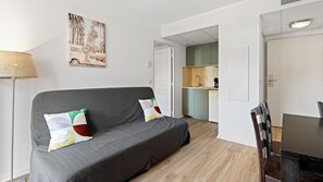 A modern living room with a grey sofa, a dining table, and a kitchen in the background. - Charming apart for 4 in the city center (Grasse)