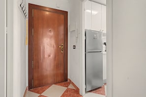 A wooden door with a brass handle, a tiled floor, and a white refrigerator in the background. - Apartment 'Beach Front Home A125' with Sea View, Wi-Fi and Air Conditioning (Torrox Costa)
