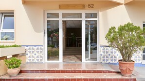 A building entrance with a number sign, a glass door, tiled walls, and potted plants. - Apartment 'Beach Front Home A125' with Sea View, Wi-Fi and Air Conditioning (Torrox Costa)