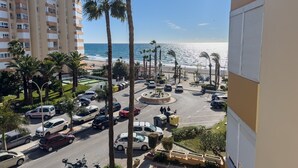 A coastal urban area with a parking lot, palm trees, and a view of the beach. - Apartment 'Beach Front Home A125' with Sea View, Wi-Fi and Air Conditioning (Torrox Costa)