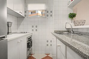 A kitchen with white cabinets, a stainless steel coffee maker, a built-in oven, and a granite countertop. - Apartment 'Beach Front Home A125' with Sea View, Wi-Fi and Air Conditioning (Torrox Costa)