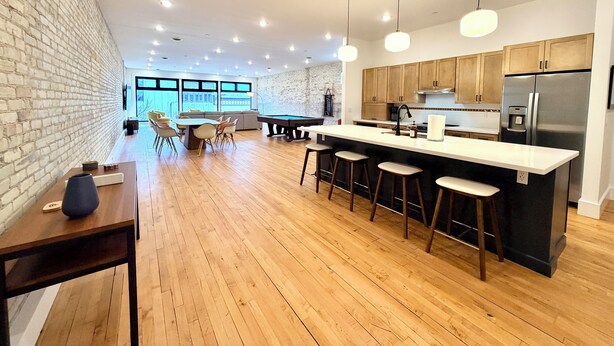 Una cocina moderna con suelo de madera, barra con taburetes y una isla grande con fregadero.