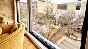 Una habitación con un ventanal grande, suelo de madera y un sillón amarillo.