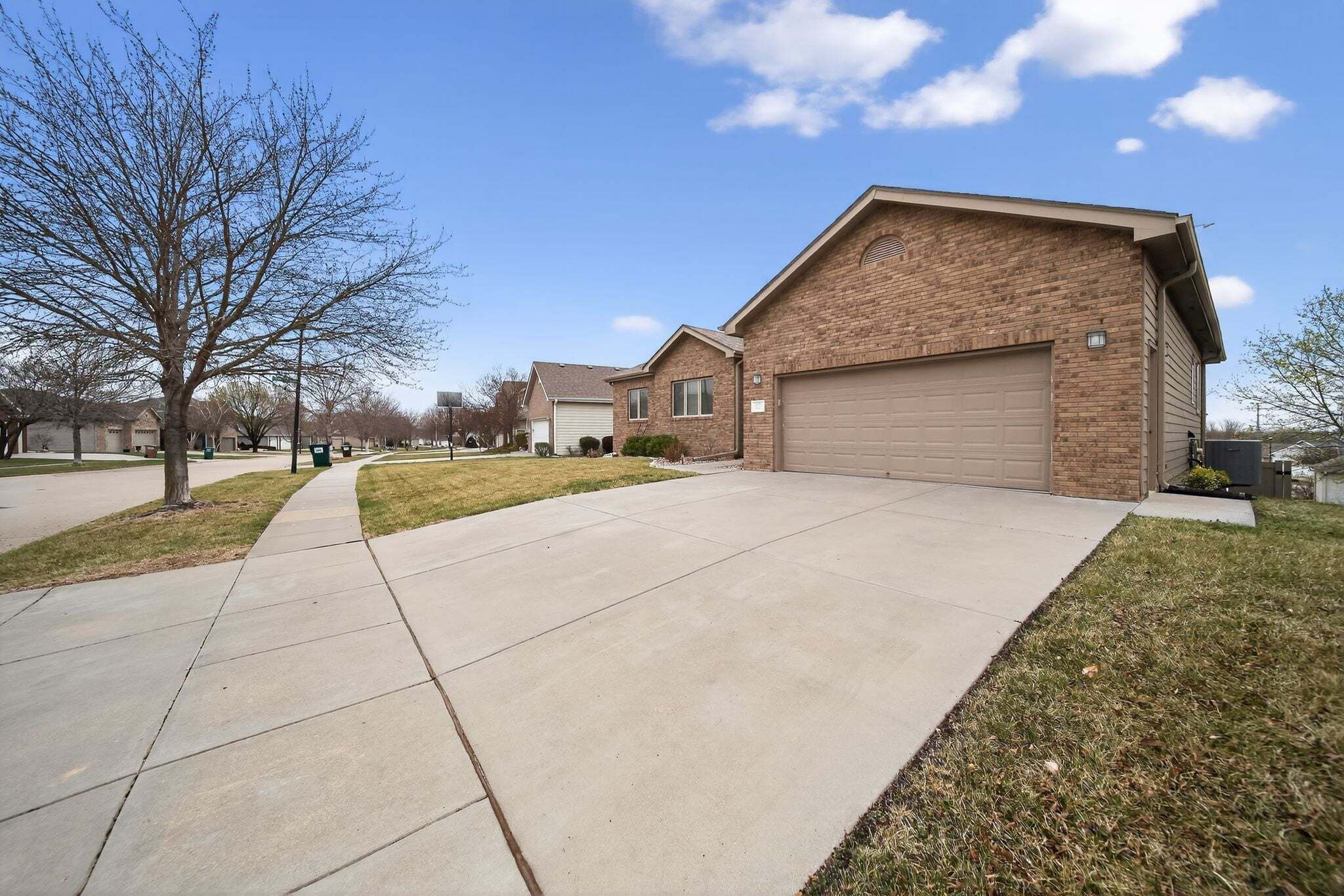 A residential area with a brick house, a garage, and a sidewalk.