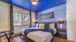 Un dormitorio moderno con una cama grande, vistas a árboles fuera y un diseño de techo único.