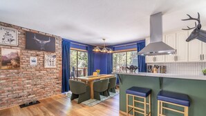 Una cocina con armarios de madera, una decoración de cabeza de ciervo y un comedor con mesa y sillas.