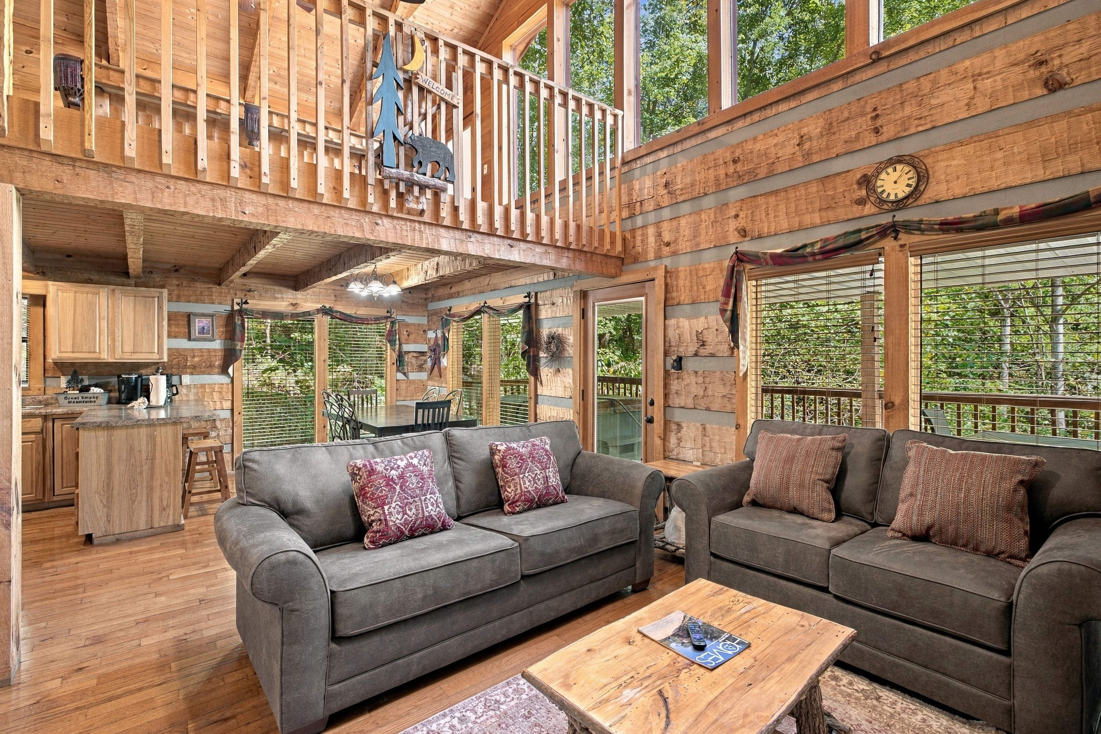 A spacious cabin with a loft bedroom, a dining area, and a living room furnished with sofas and a coffee table.