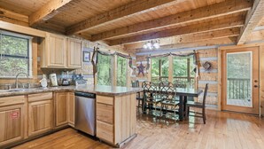 L’intérieur d’un chalet en bois comprend une cuisine, un coin repas et une grande fenêtre.