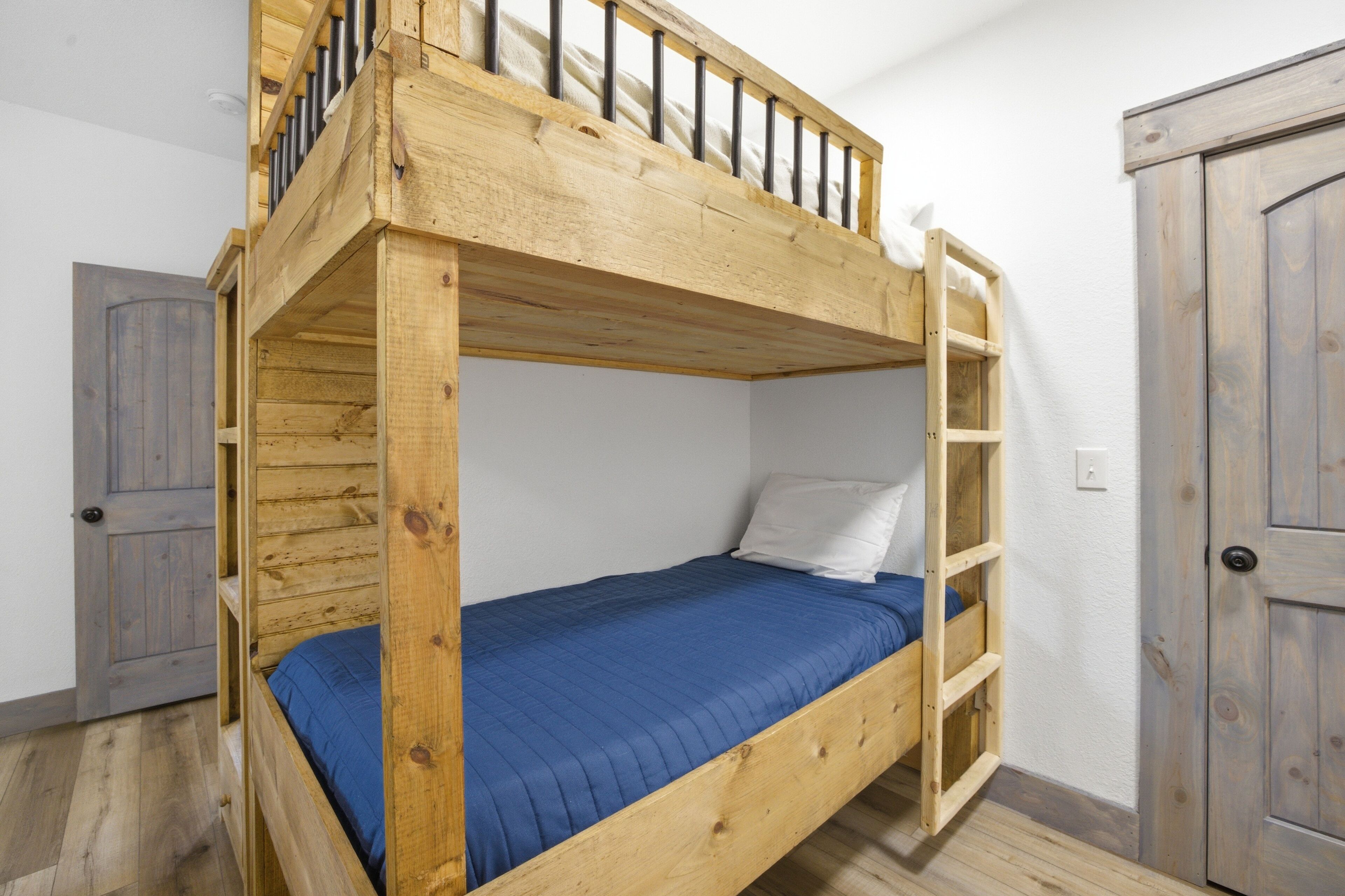 Un lit superposé avec une échelle en bois, un matelas bleu et un oreiller blanc.