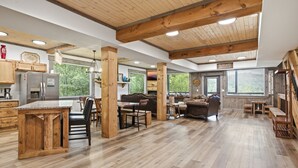 Un interior amplio con cocina, comedor y sala de estar, que presenta pisos de madera y vigas en el techo.