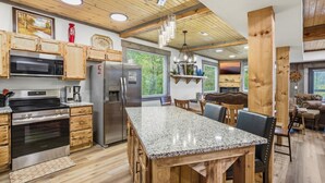 Una cocina moderna con encimeras de granito, gabinetes de madera y electrodomésticos de acero inoxidable, además de un comedor con mesa y sillas de madera.