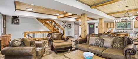 A spacious living room with a wooden staircase, leather sofas, and a dining area.
