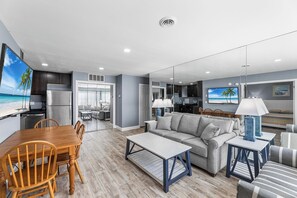 A modern living room with a sofa, coffee table, and dining area. - Club Ocean Villas 63 (Ocean City)