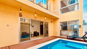 A modern two-story building with a swimming pool, sliding glass doors, and outdoor seating. - Tulum Paradise | 4BR Home with Private Pool (Tulum)