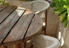 Ein runder Holztisch mit vier weißen Korbstühlen.