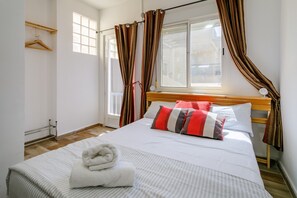Un llit ben fet amb una tovallola blanca, un panell de capçal de fusta i roba de llit a ratlles.
