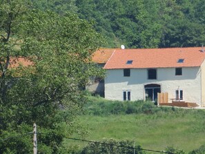 Ein zweistöckiges Gebäude mit rotem Ziegeldach, einem zentralen Eingang und einem kleinen Fenster im Obergeschoss.