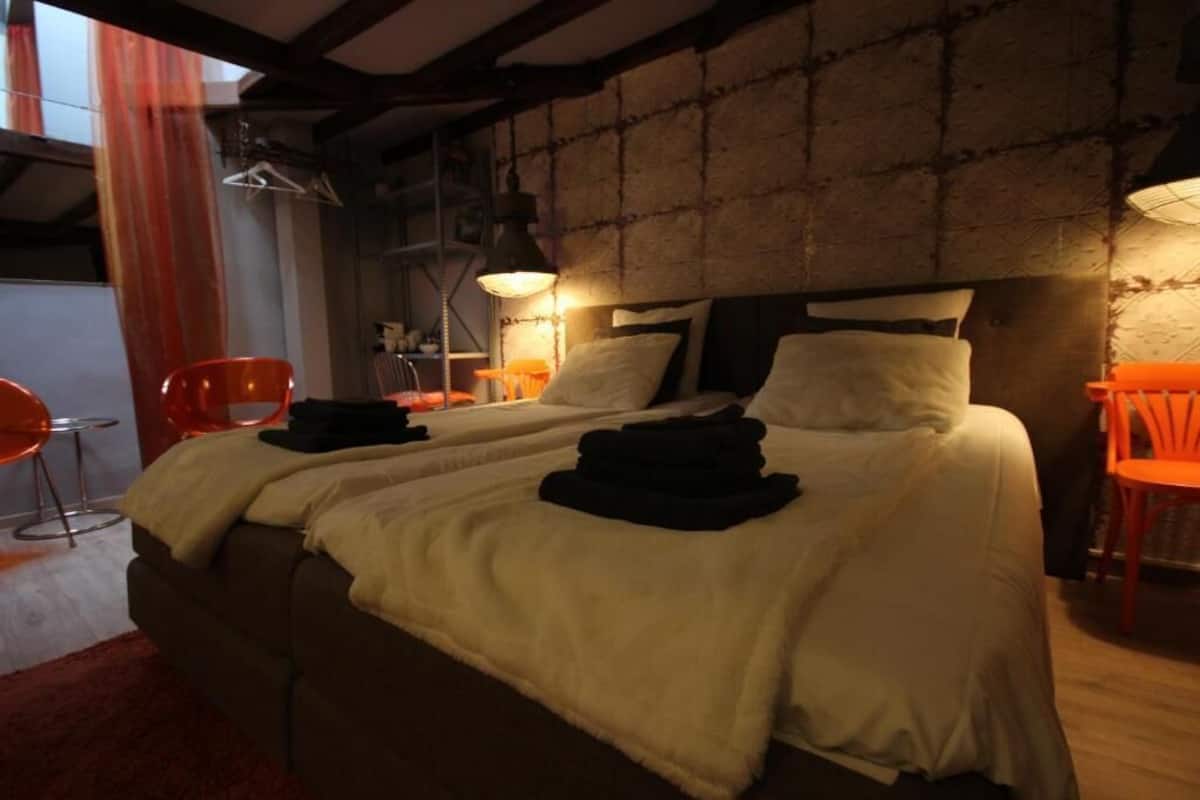 Una cama doble con cabecera, dos mesitas de noche y una silla roja.