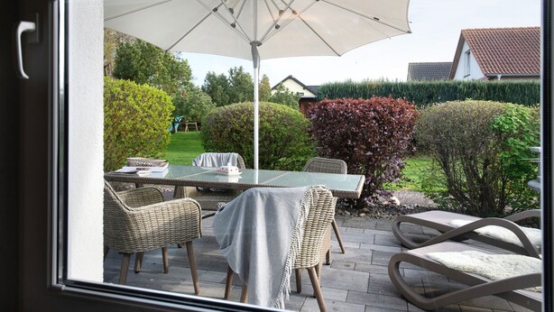 Une terrasse avec une table, des chaises et un parasol.