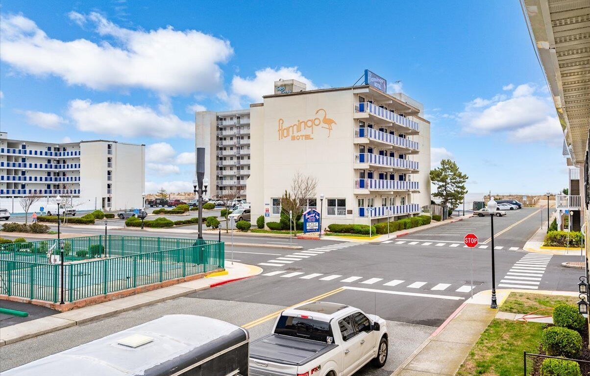 A hotel with a prominent sign, a parking lot, and a street intersection.