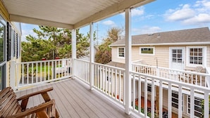 A covered porch with a white railing, wooden deck, and a view of a house with a lawn and trees. - Great Location for Family fun at Jolly Roger and Boardwalk! (Ocean City)