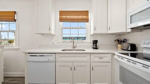 A kitchen with white cabinets, a dishwasher, a sink, a stove, and a window with blinds. - Great Location for Family fun at Jolly Roger and Boardwalk! (Ocean City)